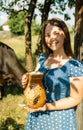 Young farmer woman smiling on camera carries jug of milk after milking cow on farm pasture. Natural dairy products from farmer Royalty Free Stock Photo