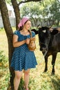 Young farmer woman smiling on camera carries jug of milk after milking cow on farm pasture. Natural dairy products from farmer Royalty Free Stock Photo