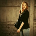 Young fashion blond business woman with handbag walking on city street Royalty Free Stock Photo