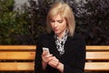 Young fashion blond business woman using cell phone on city street Royalty Free Stock Photo