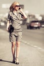 Young fashion blond woman calling on cell phone on city street Royalty Free Stock Photo