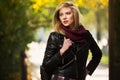 Young fashion blond woman in leather jacket in autumn park