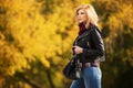 Young fashion blond woman in leather jacket in autumn park Royalty Free Stock Photo