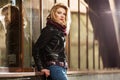 Young fashion blond woman in leather jacket at the mall window