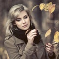 Young fashion woman in classic beige coat walking in autumn park