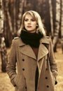 Young fashion woman in classic beige coat walking in autumn park