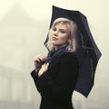 Young fashion woman with umbrella walking in a fog outdoor Royalty Free Stock Photo