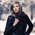 Young fashion blonde woman with handbag in black leather jacket and snood scarf