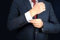 Young fashion buisness man in a blue/navy suit touching at his cufflinks