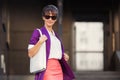 Young fashion business woman in purple blazer and sunglasses walking in city street Royalty Free Stock Photo