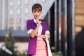 Young fashion business woman wearing purple blazer walking in city street Royalty Free Stock Photo