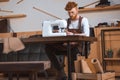 young fashion designer in apron and eyeglasses working with sewing machine