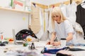 Young fashion designer working on her atelier. Fashion Design Studio with Working Personal Computer, Hanging Clothes, Coffee and Royalty Free Stock Photo