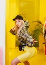 Young fashion girl blogger with black cap on the head dressed in a stylish black and yellow jacket and yellow shorts Royalty Free Stock Photo