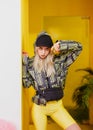 Young fashion girl blogger with black cap on the head dressed in a stylish black and yellow jacket and yellow shorts Royalty Free Stock Photo