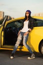 Young fashion hipster woman in ripped jeans leaning on her car Royalty Free Stock Photo