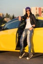 Young fashion hipster woman in ripped jeans leaning on her car Royalty Free Stock Photo