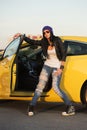 Young fashion hipster woman in ripped jeans leaning on her car Royalty Free Stock Photo