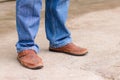 Young fashion man`s legs in blue jeans and brown boots on concre Royalty Free Stock Photo