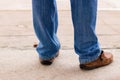 Young fashion man`s legs in blue jeans and brown boots on concre Royalty Free Stock Photo