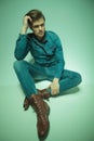 Young fashion man sitting on the floor, fixing his hair Royalty Free Stock Photo