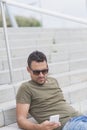 Young fashion man sitting on the steps while using a smartphone Royalty Free Stock Photo