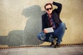 Young fashion man with tablet computer sitting at the wall Royalty Free Stock Photo