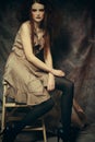 Young fashion model with creative make up sitting on a stool in Royalty Free Stock Photo