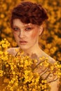 Young fashion model portrait with ginger hair and blue eyes in yellow rapeseed field. Royalty Free Stock Photo