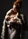 Young fashion mother woman standing in mink coat breastfeeding her infant child Royalty Free Stock Photo