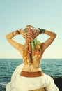 Young fashion woman back, girl sitting on a stone against seascape