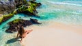 Young fashion woman in bikini sitting on tropical beach. Beautiful girl in black swimsuit stands on the shore. Caribbean Royalty Free Stock Photo