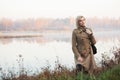 Young fashion woman in classic beige coat walking in a fog outdoor