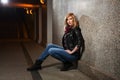 Young fashion woman in leather jacket sitting at the wall