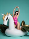 Young fashion woman relaxing with big inflatable unicorn pegasus float mattress in pink bikini for swimming pool Royalty Free Stock Photo