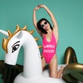 Young fashion woman relaxing with big inflatable unicorn pegasus float mattress in pink bikini for swimming pool Royalty Free Stock Photo