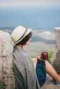 Young fashion woman sitting on a top of the mountain drinking tea with beautiful mountains and ocean view on the background Royalty Free Stock Photo