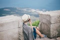 Young fashion woman sitting on a top of the mountain drinking tea with beautiful mountains and ocean view on the background Royalty Free Stock Photo