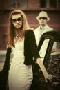 Young fashion woman in sunglasses next to vintage car