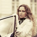 Young fashion woman in white trench coat outside her car