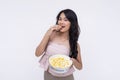 A young fashionable asian woman eating a bowl of butter flavored popcorn. taking a bite of a single kernel while looking at camera