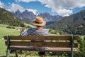 Young fashionable dressed female in straw hat sitting on a bench enjoying Santa Maddalena village view and stunning picturesque Royalty Free Stock Photo