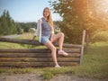 Young fashionable happy blonde woman posing in rural landscape.