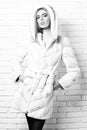 Young fashionable pretty woman or girl with beautiful long blonde hair in waist coat of white fur with hood and Royalty Free Stock Photo