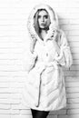 Young fashionable pretty woman or girl with beautiful long blonde hair in waist coat of white fur with hood and Royalty Free Stock Photo