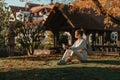 Young Fashionable Teenage Girl With Smartphone In Europian Park In Autumn Sitting At Smiling. Trendy Young Woman In Fall Royalty Free Stock Photo