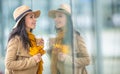 Young fashionable woman is doing window shopping holding takeaway coffee and autumn leaves Royalty Free Stock Photo