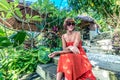 Young fashionable woman in red dress in a tropical garden. Portrait of happy woman relaxing on Bali island, Indonesia. Royalty Free Stock Photo