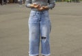 A young fashionable woman in ripped wide jeans is standing on the street