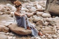 Young fashionable woman sitting on the stone beach